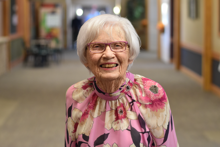 A smiling senior woman in a floral blouse