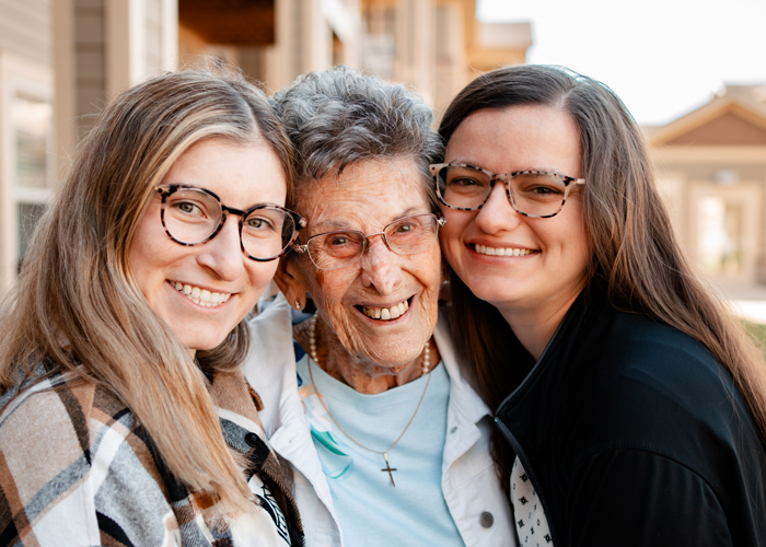 Three smiling women posing closely together outdoors