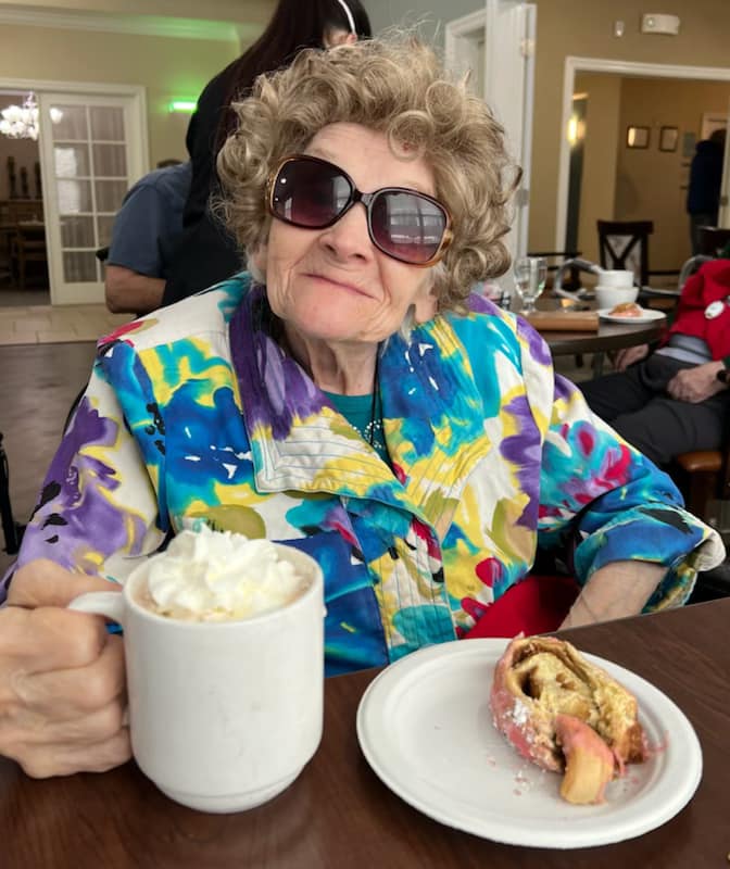 Resident enjoying dessert and coffee in a lively indoor space