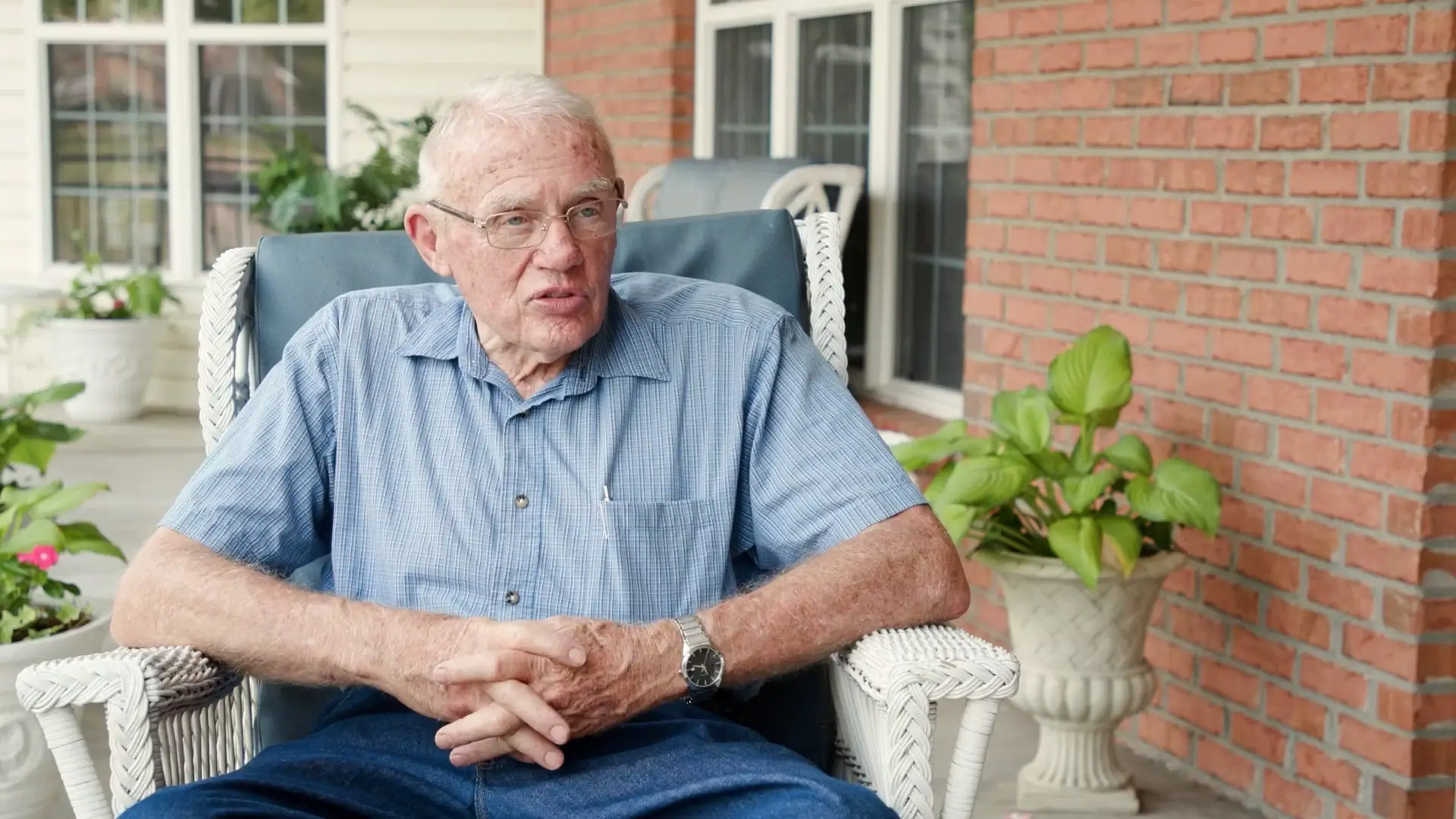 An elderly man sitting on a chair on a porch