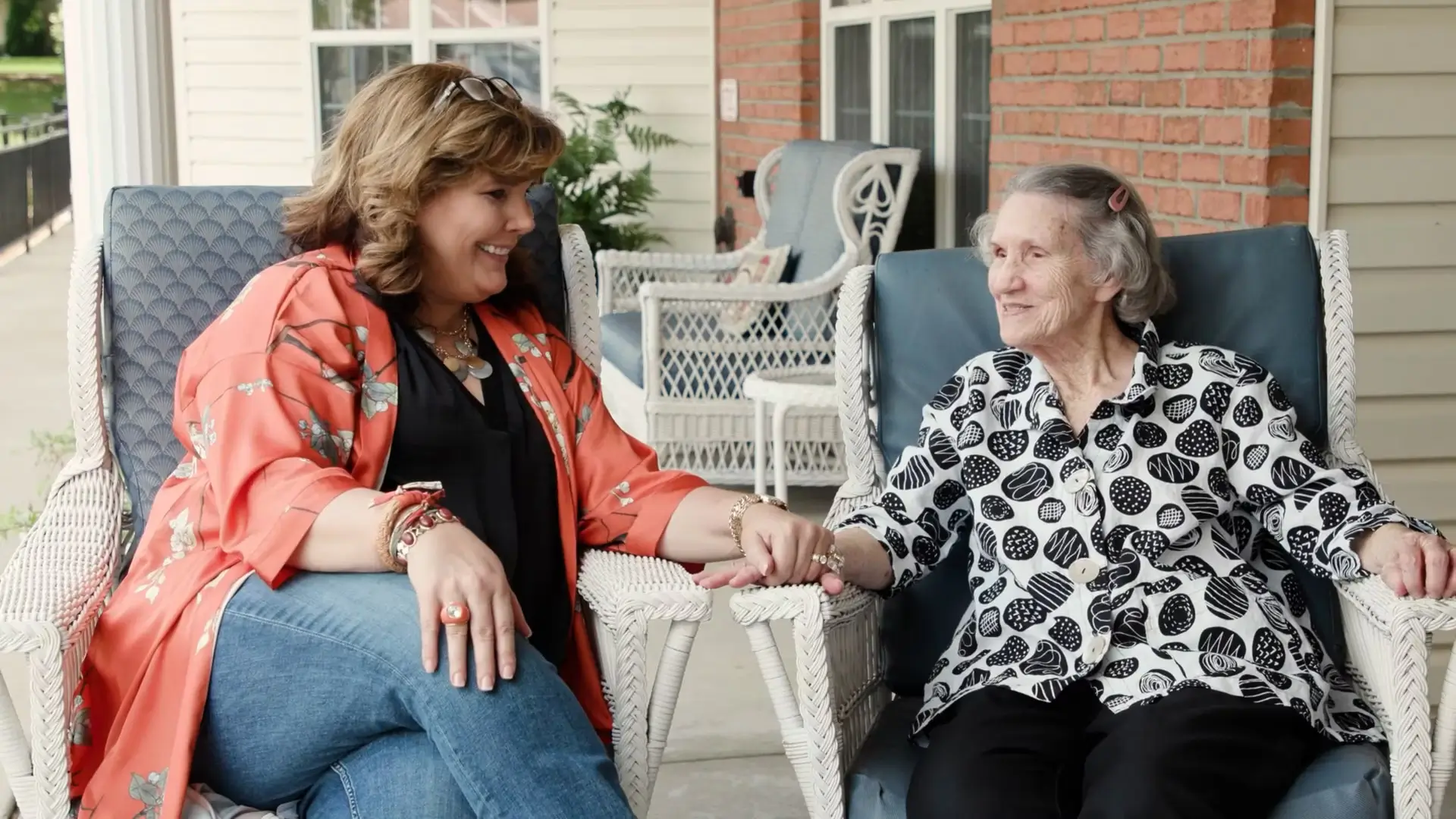 Two women sitting outside holding hands and smiling