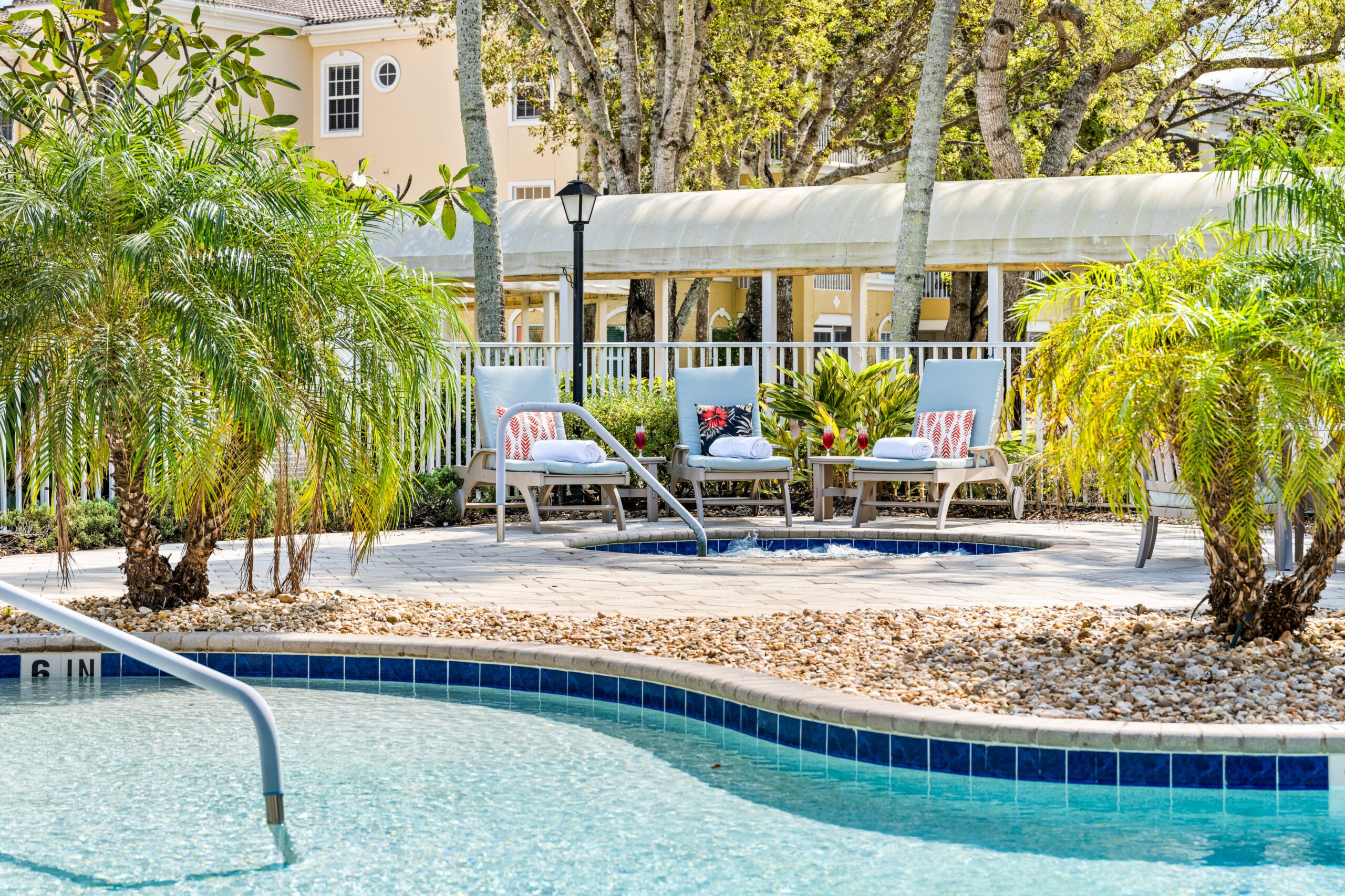 Outdoor pool area with lounge chairs and palm trees