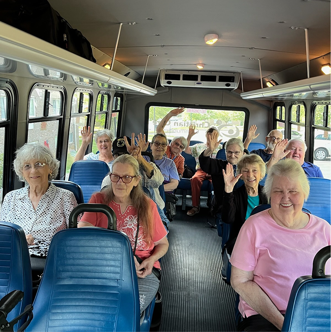 Residents happily waving on a facility bus.