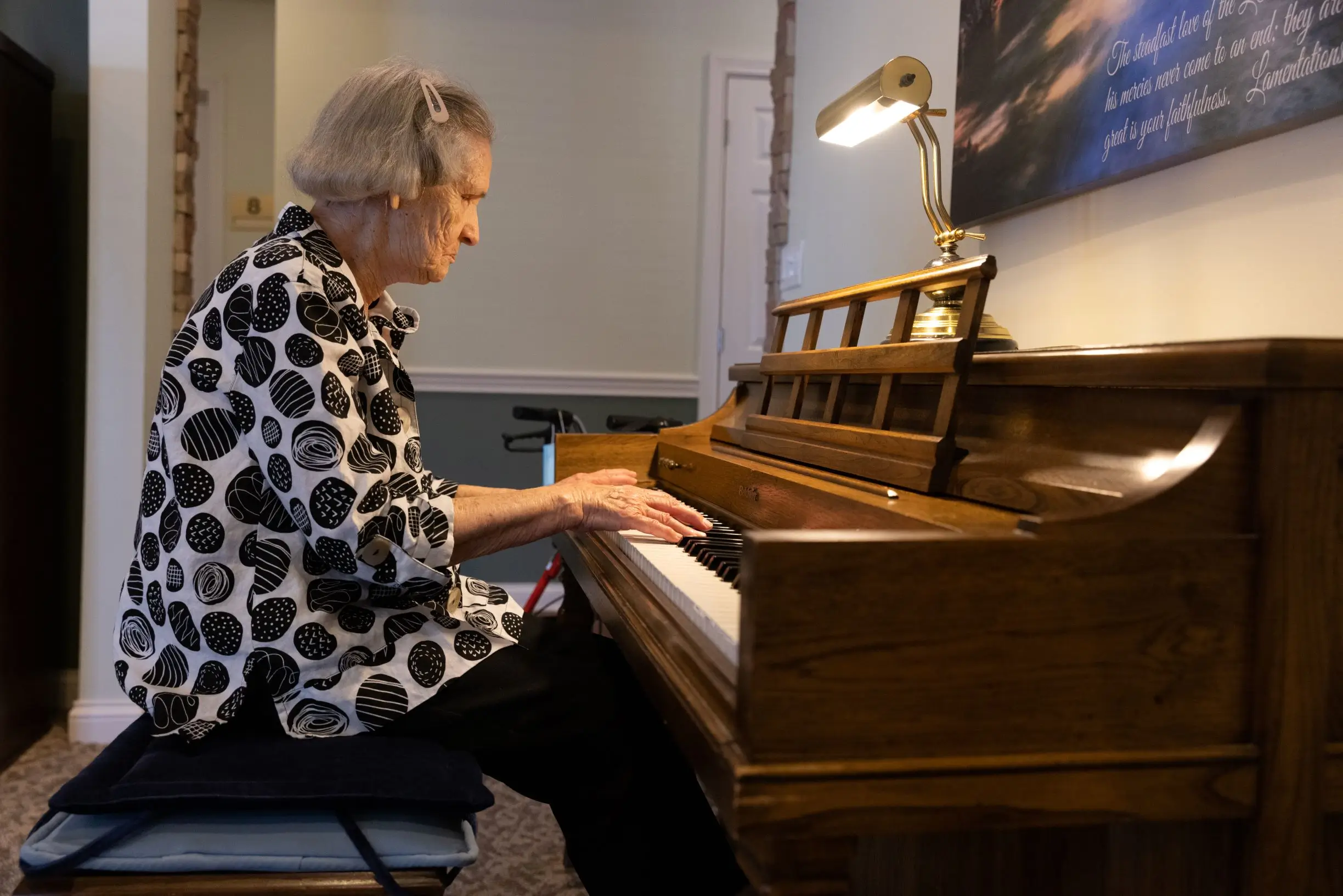 Resident playing piano in a cozy interior space