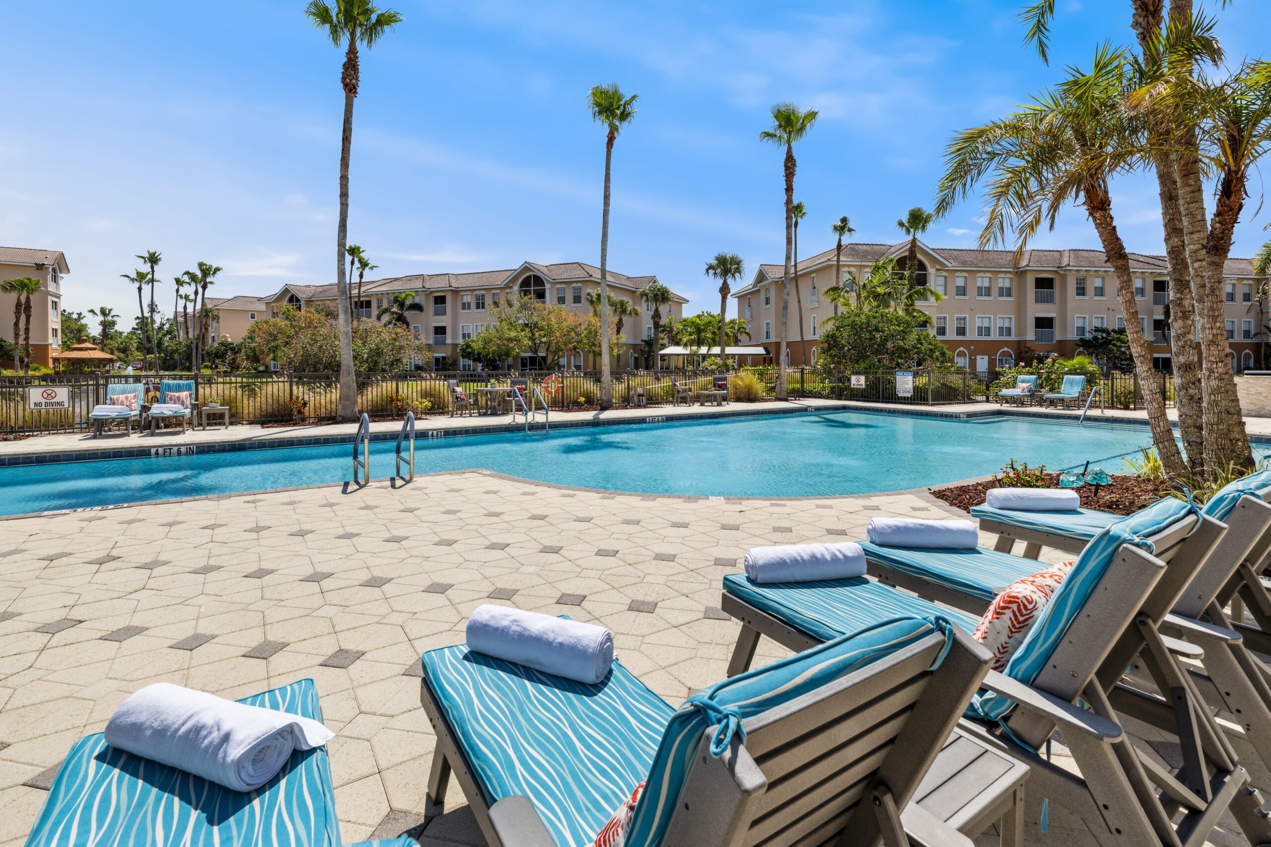 Outdoor pool area with lounge chairs and palm trees