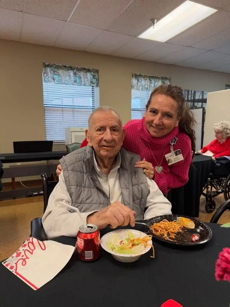 A resident enjoying a meal with a staff member in the dining room