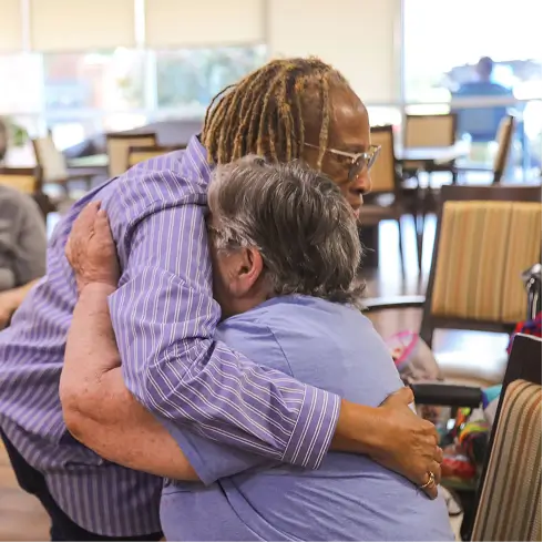 Two residents sharing a warm embrace in a common area