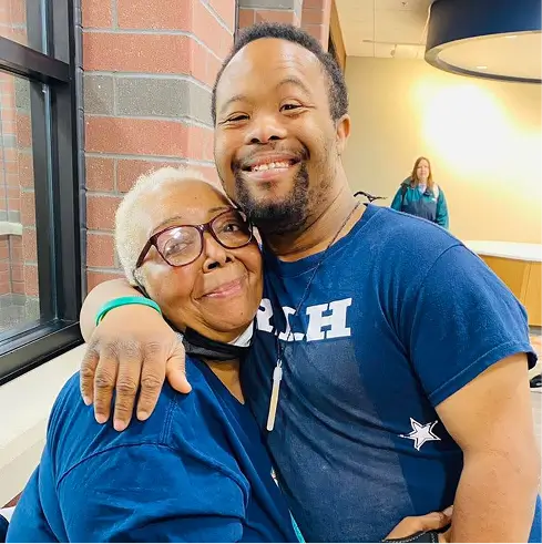 Two residents smiling and embracing in a facility interior