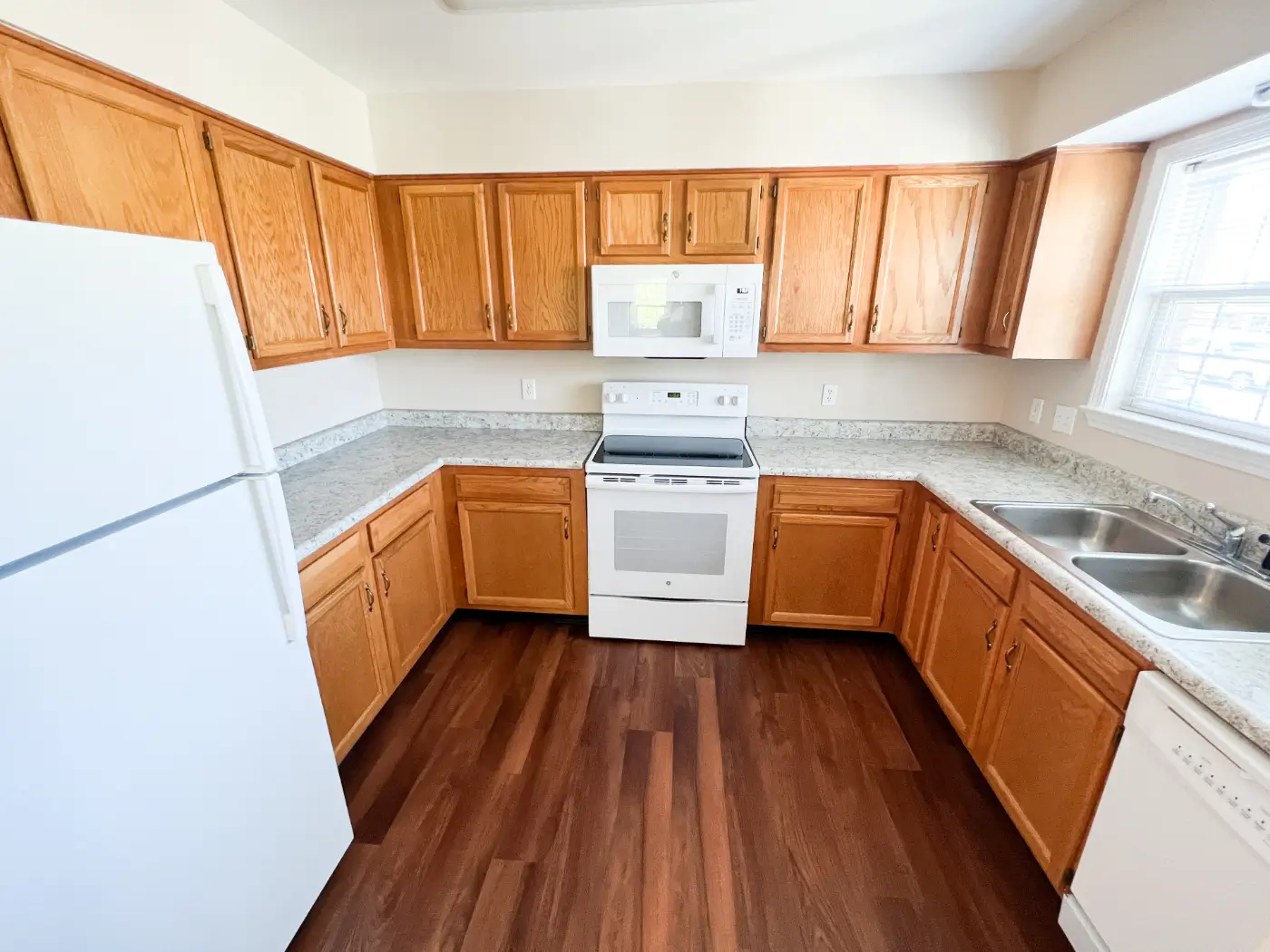Bright kitchen area with wooden cabinets and appliances