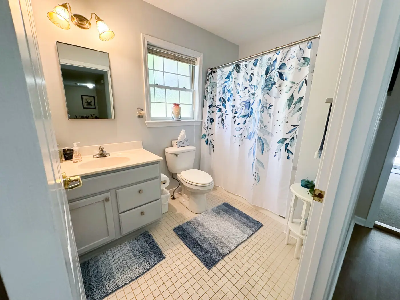 Brightly lit bathroom with floral shower curtain