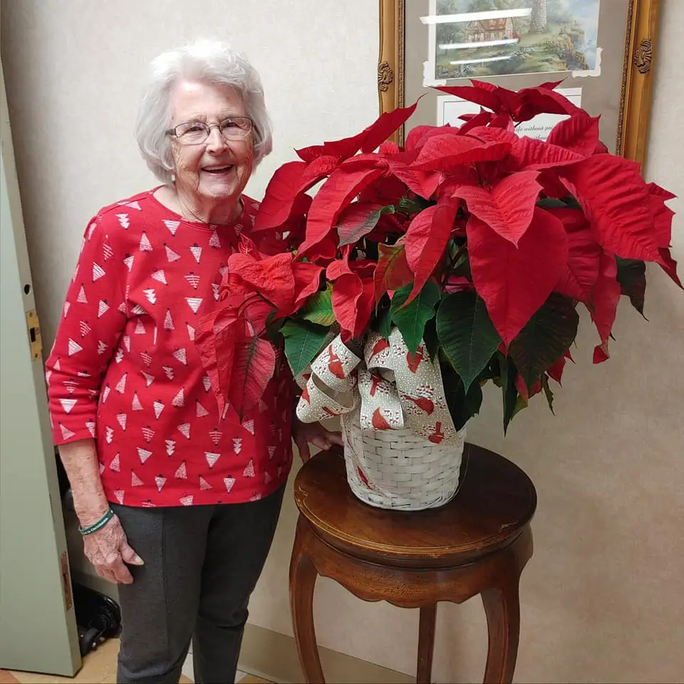 Resident with a red poinsettia plant in a common area