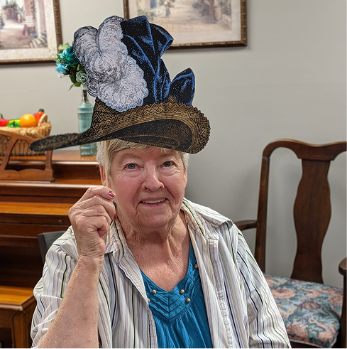 Senior resident posing with a decorative hat in a common area