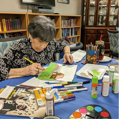 Resident engaged in an art activity at a table