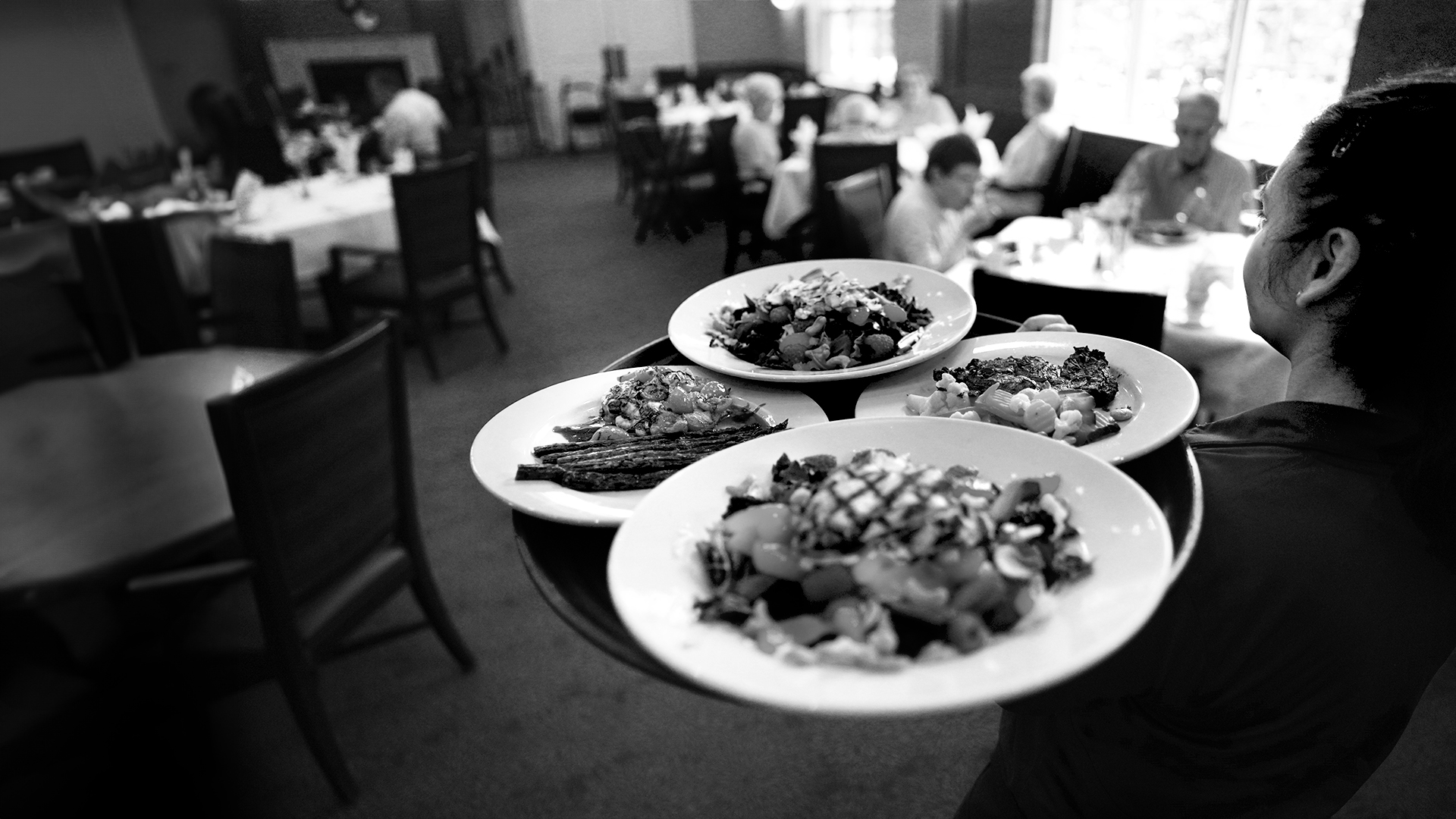 Staff serving meals in a dining room full of residents