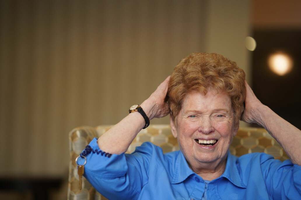 A joyful senior woman smiling in a cozy chair