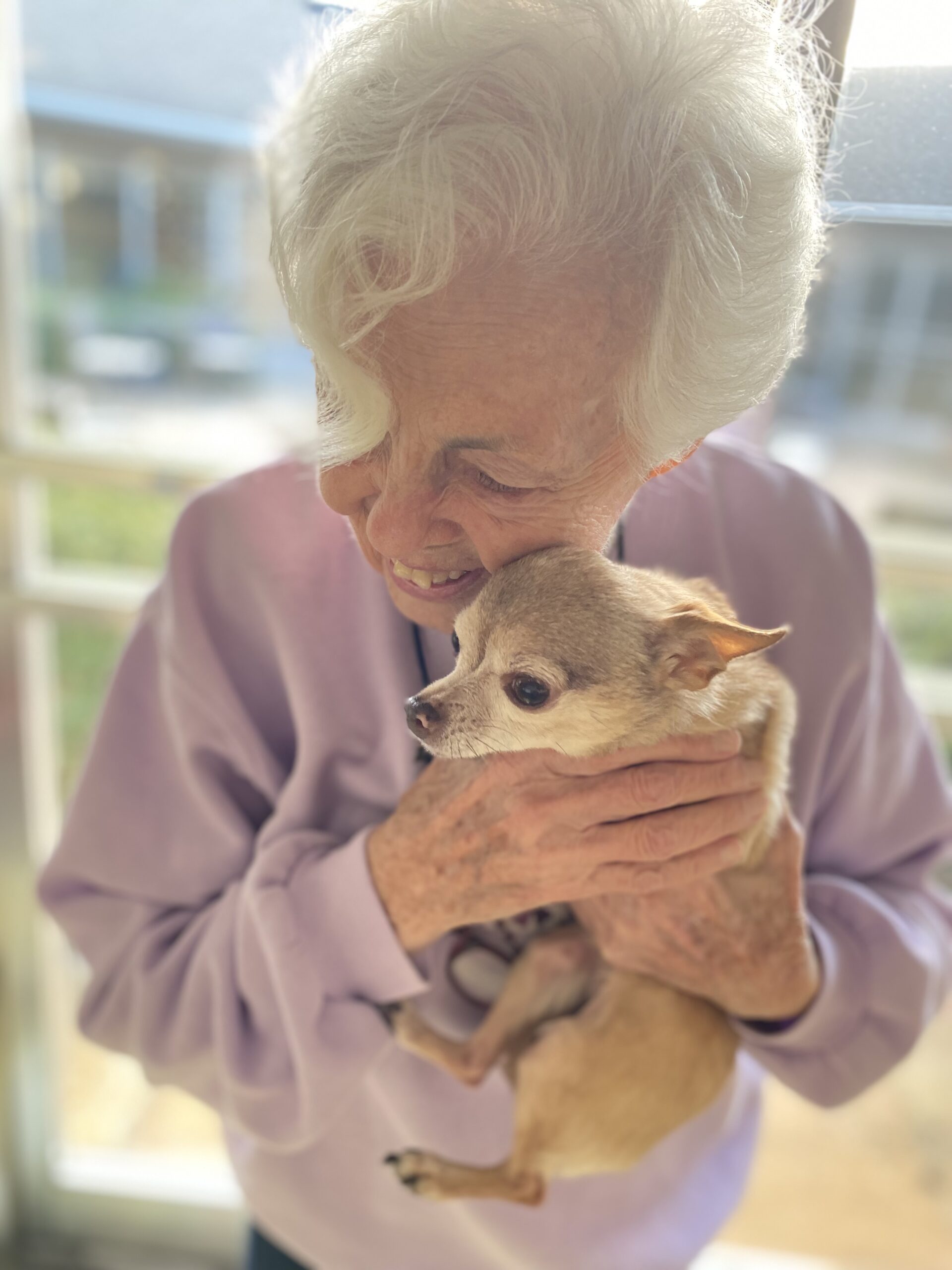 A resident smiling while holding a small dog