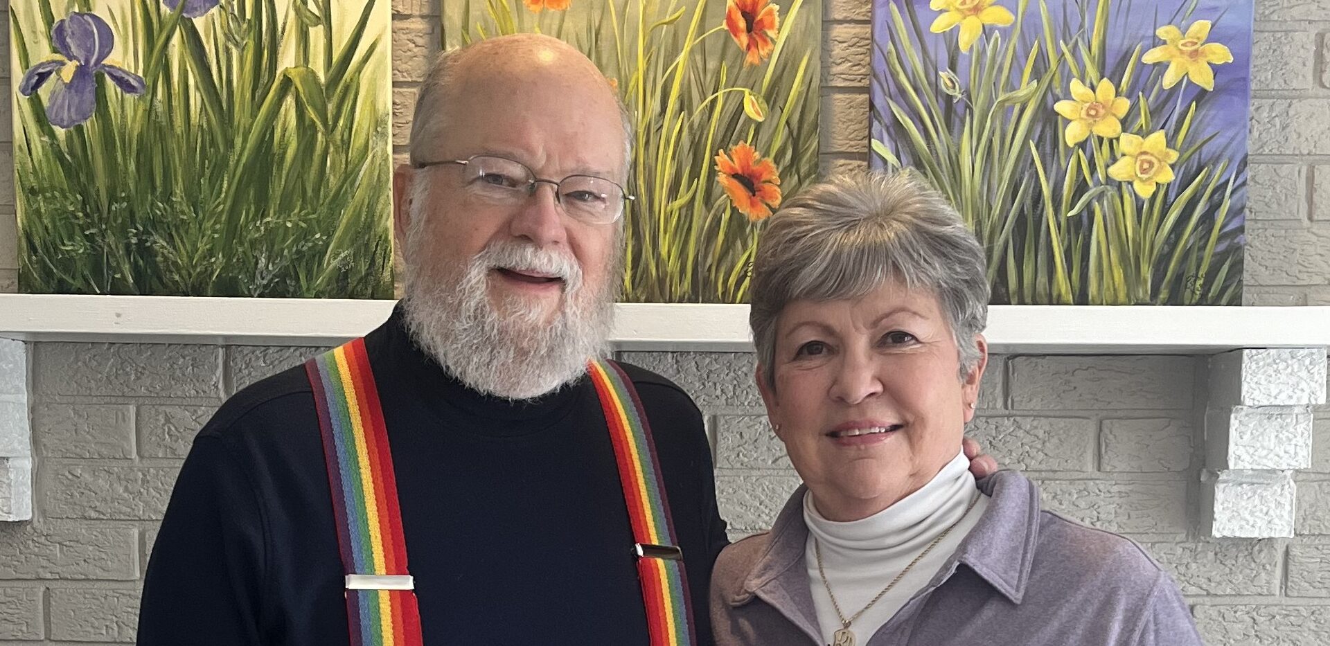 Two residents smiling in a common area with flower paintings