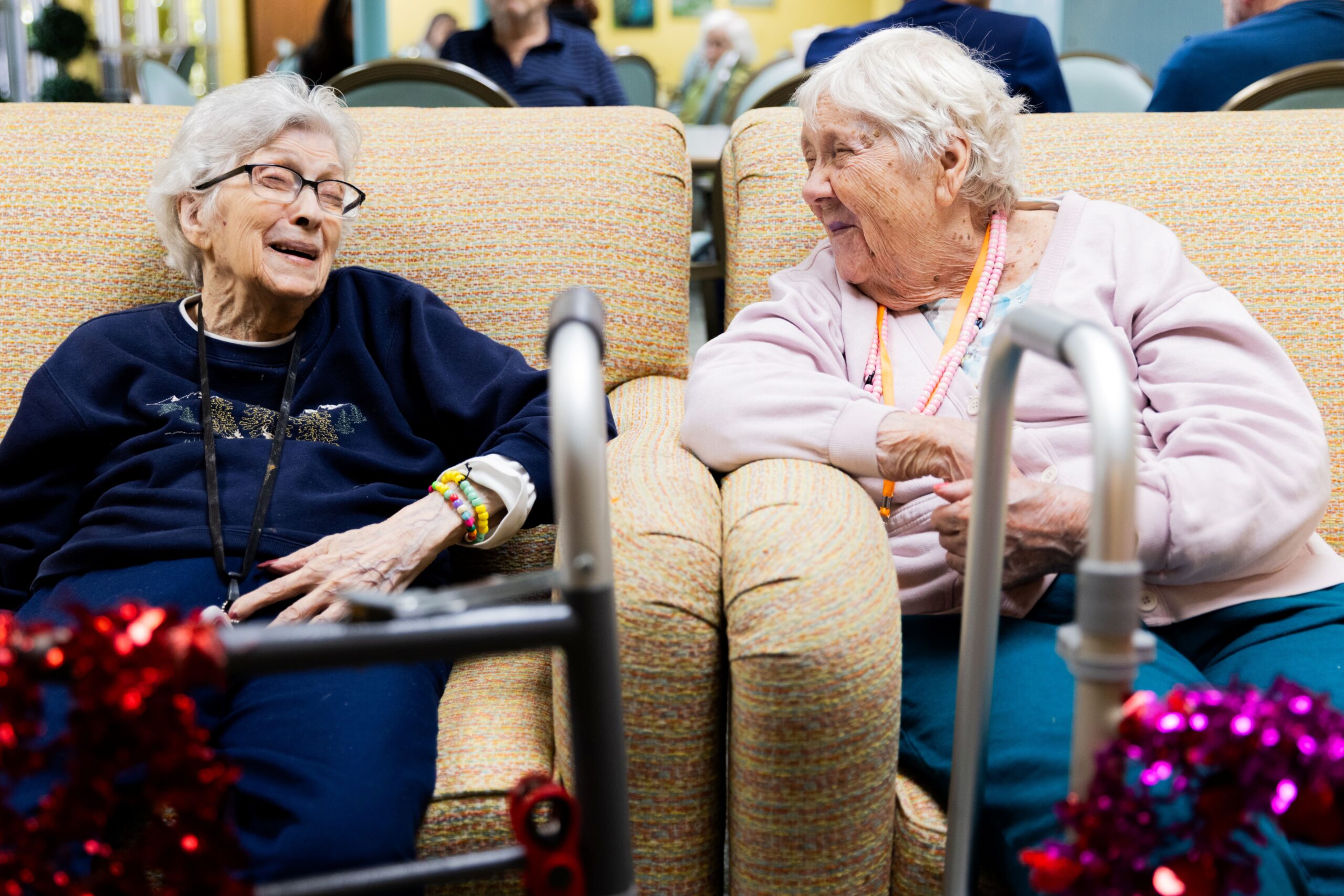 Two residents laughing on a couch in the common area