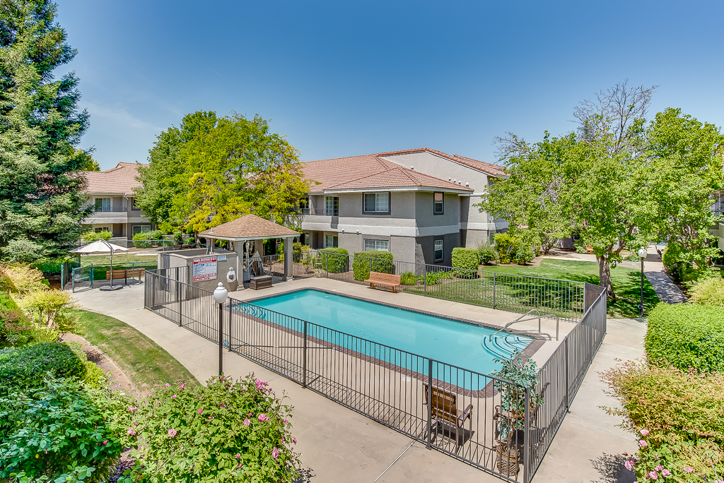 Outdoor pool area surrounded by green landscaping