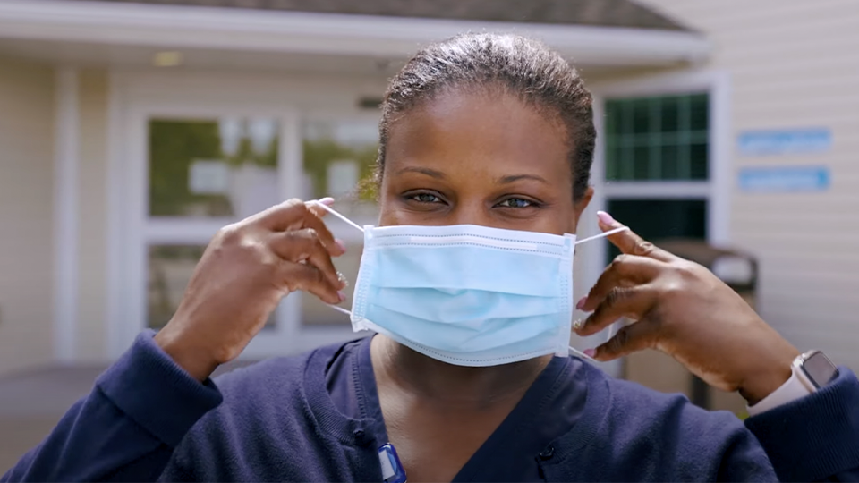 Staff member adjusting her face mask outside the facility
