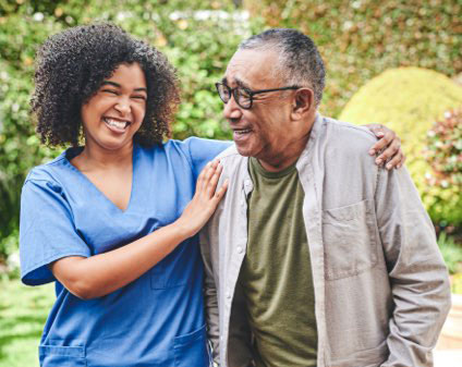 A staff member and resident smiling in a garden
