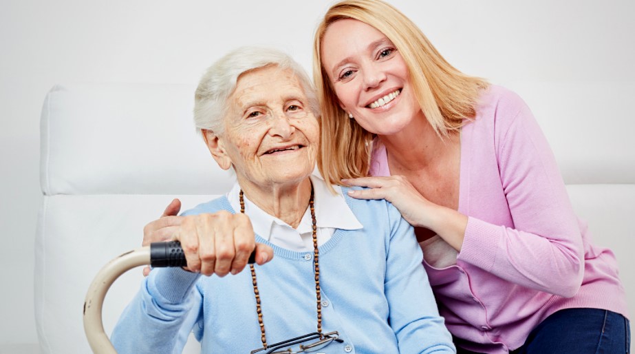 An elderly woman with her caregiver smiling together