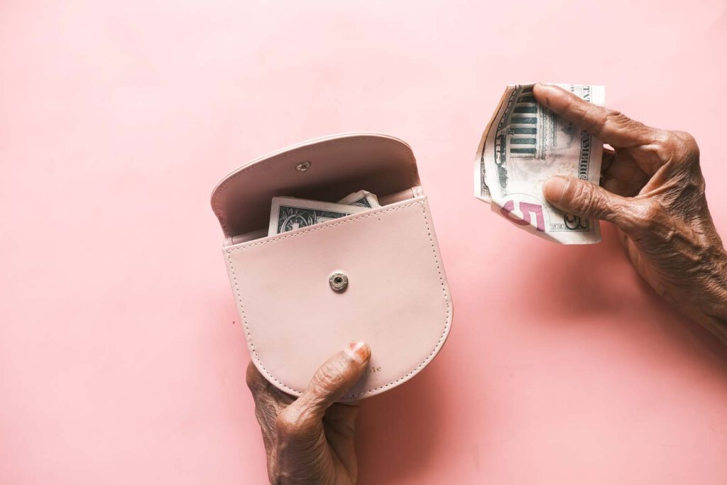 Elderly hands holding a wallet with cash