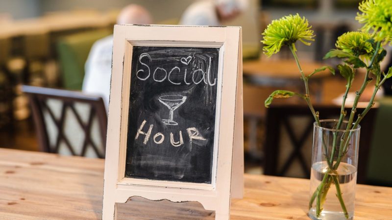 Chalkboard sign for social hour with a flower vase