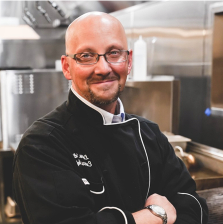 Chef in a kitchen, smiling and wearing an apron