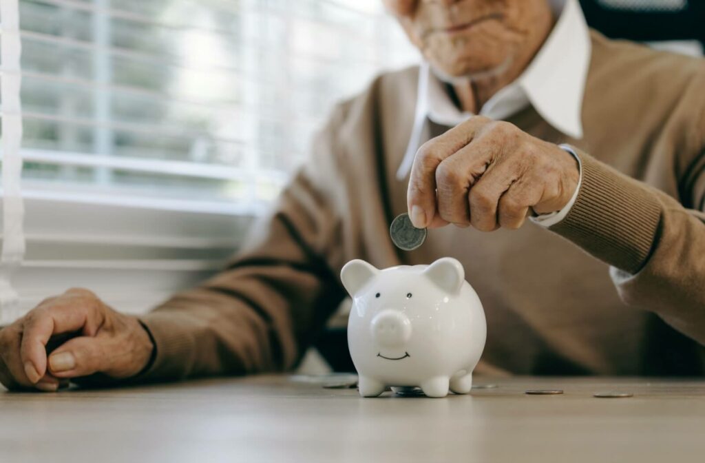 An elderly person saving coins in a piggy bank
