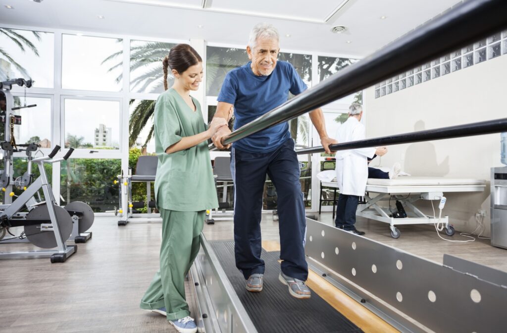 A senior man walking with assistance in a therapy room
