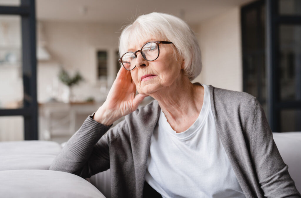 An elderly woman thoughtfully gazing while sitting indoors