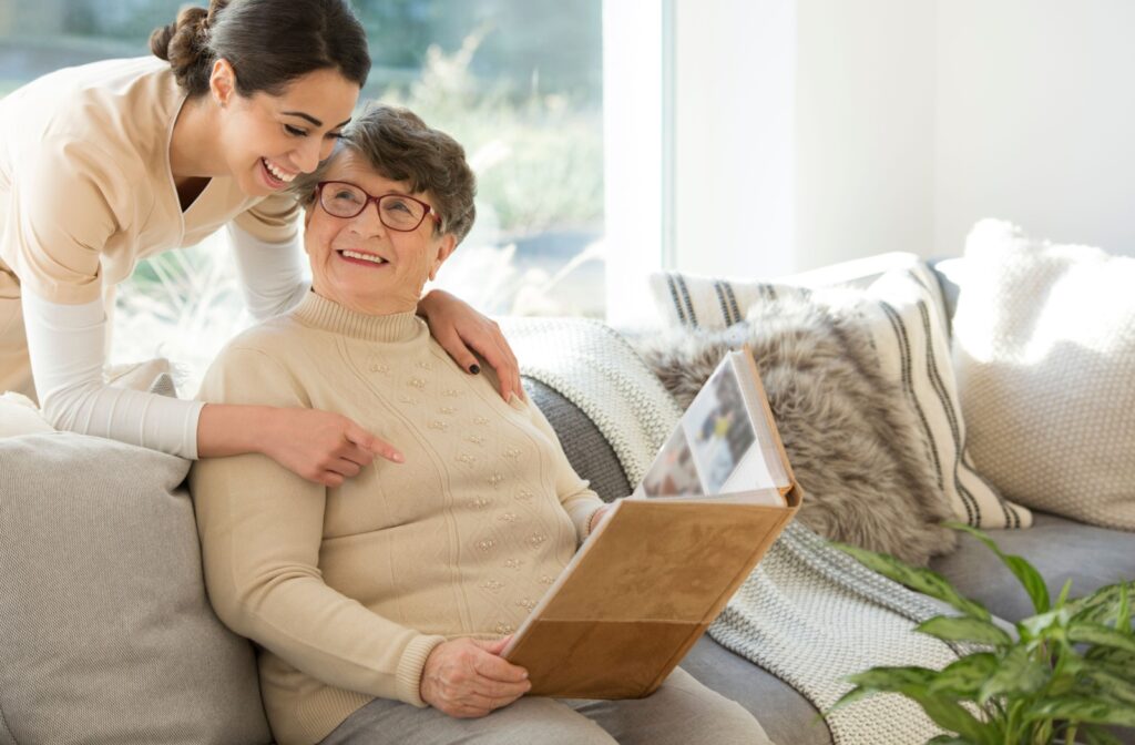 A caregiver interacts with a smiling resident sharing a photo album