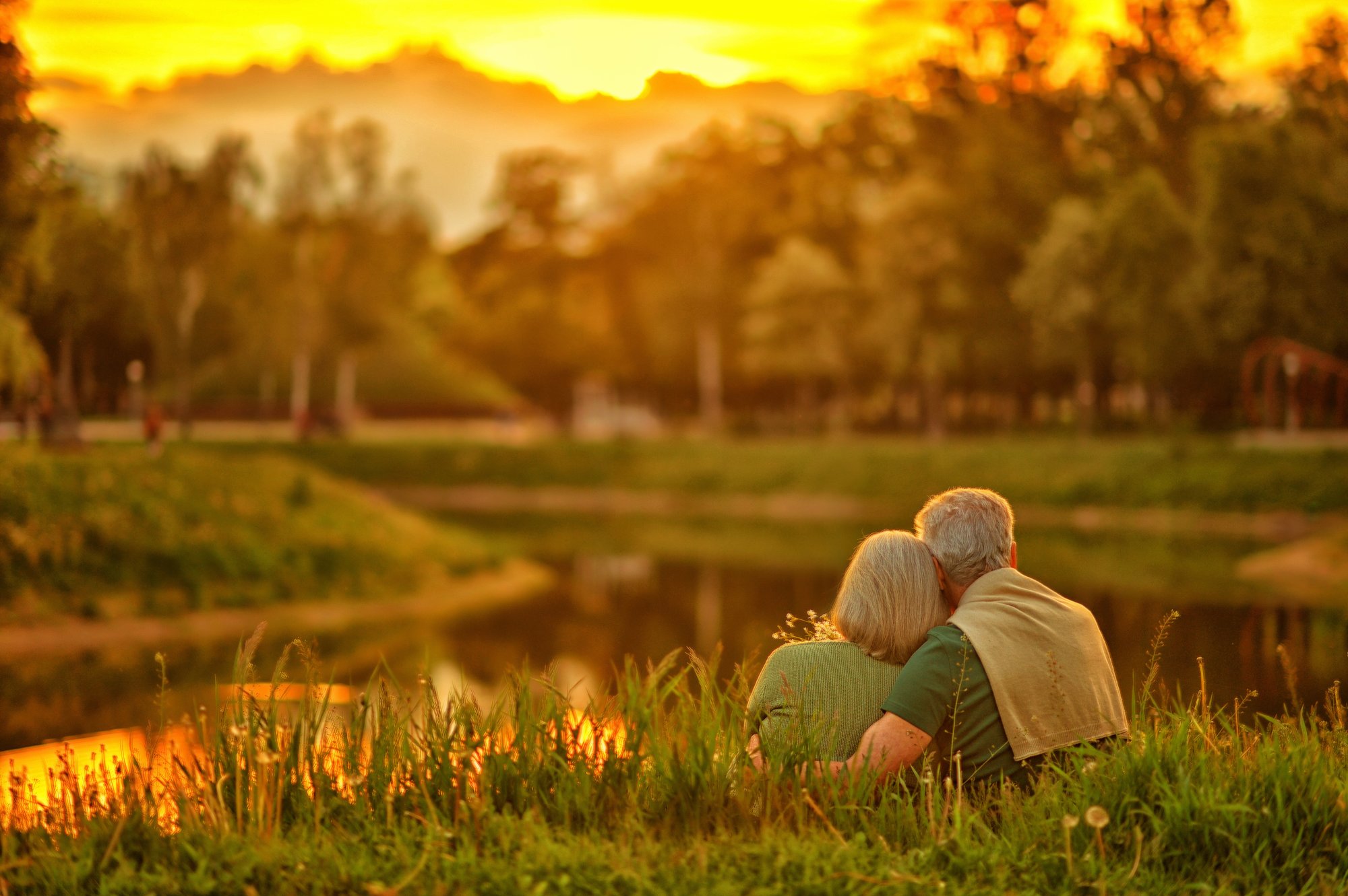 Older couple enjoying a sunset by a lake.
