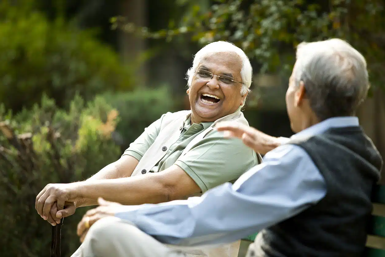 Two elderly men laughing together in a garden.