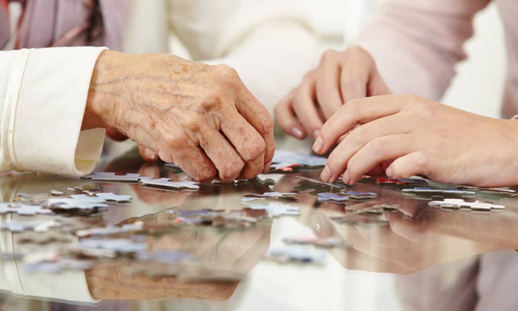 Close-up of hands assembling a puzzle together.