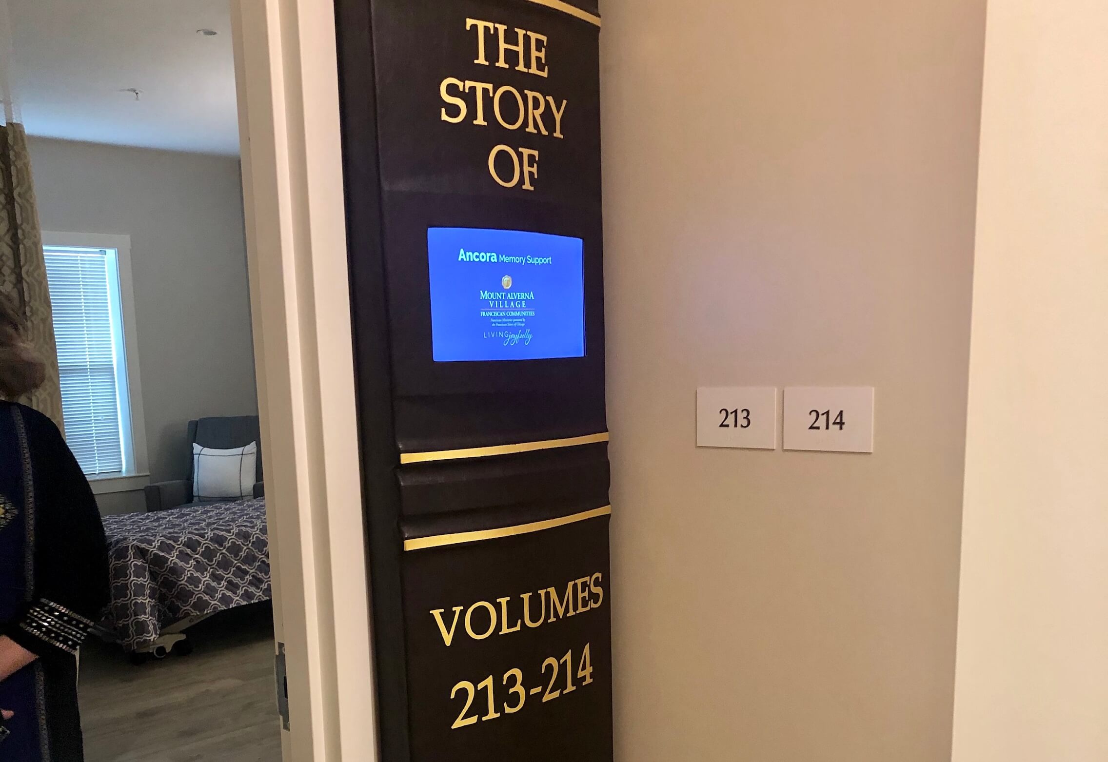Interior hallway with room numbers and a display screen.