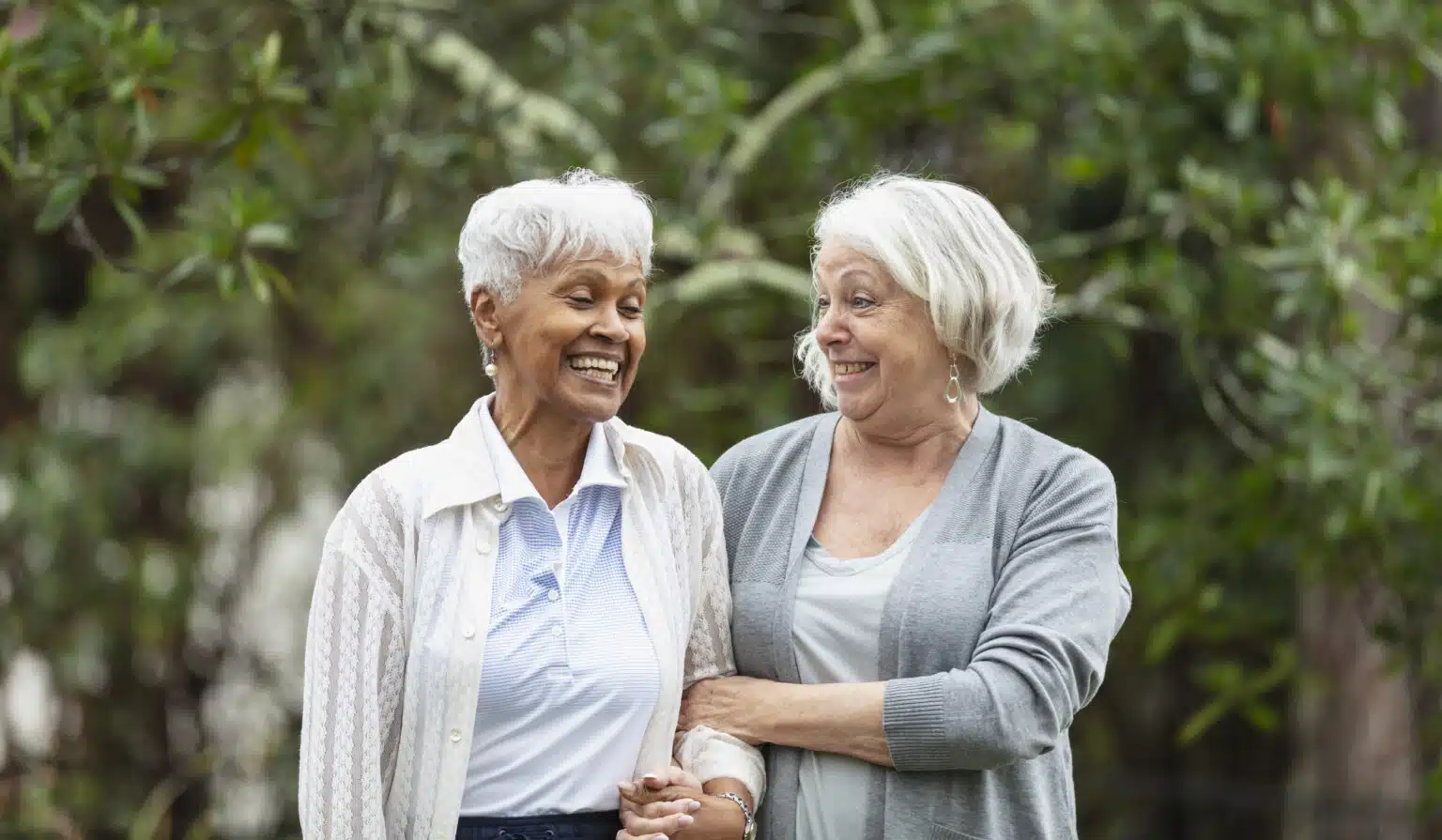 Two elderly women smiling outdoors together