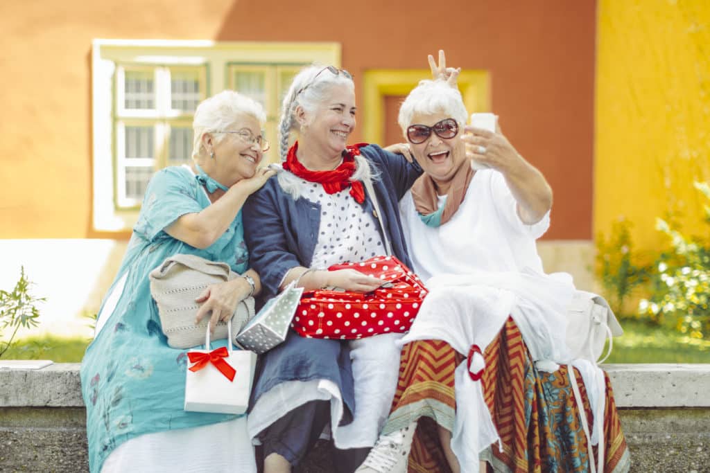 Three smiling senior women taking a selfie outdoors.