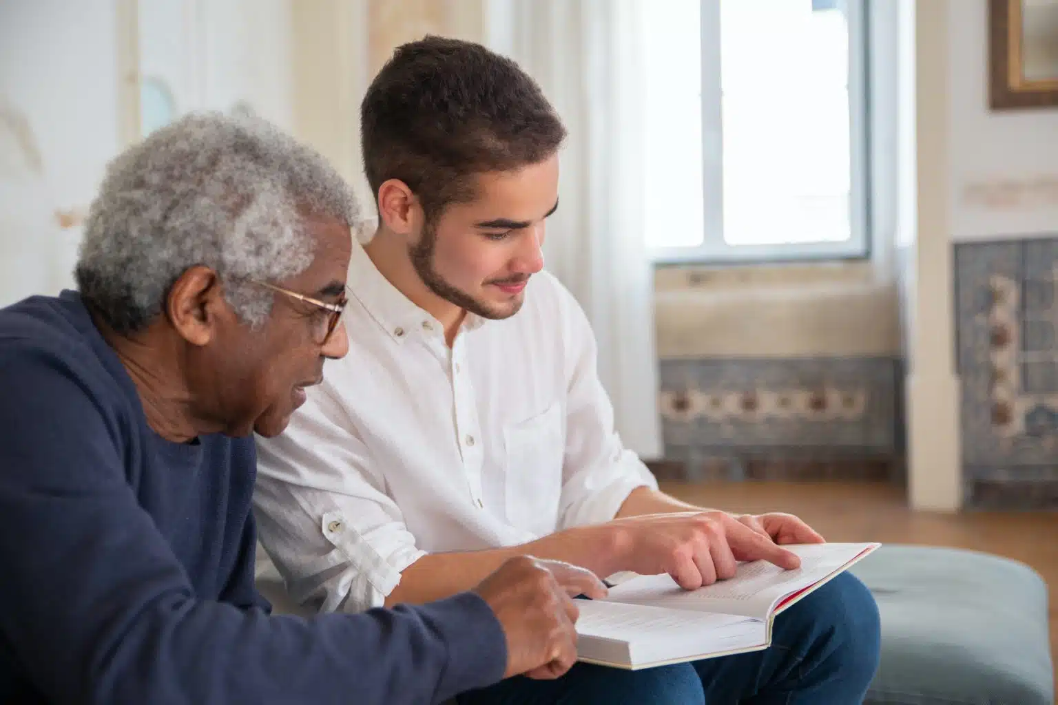 An older man and a younger man reading together.