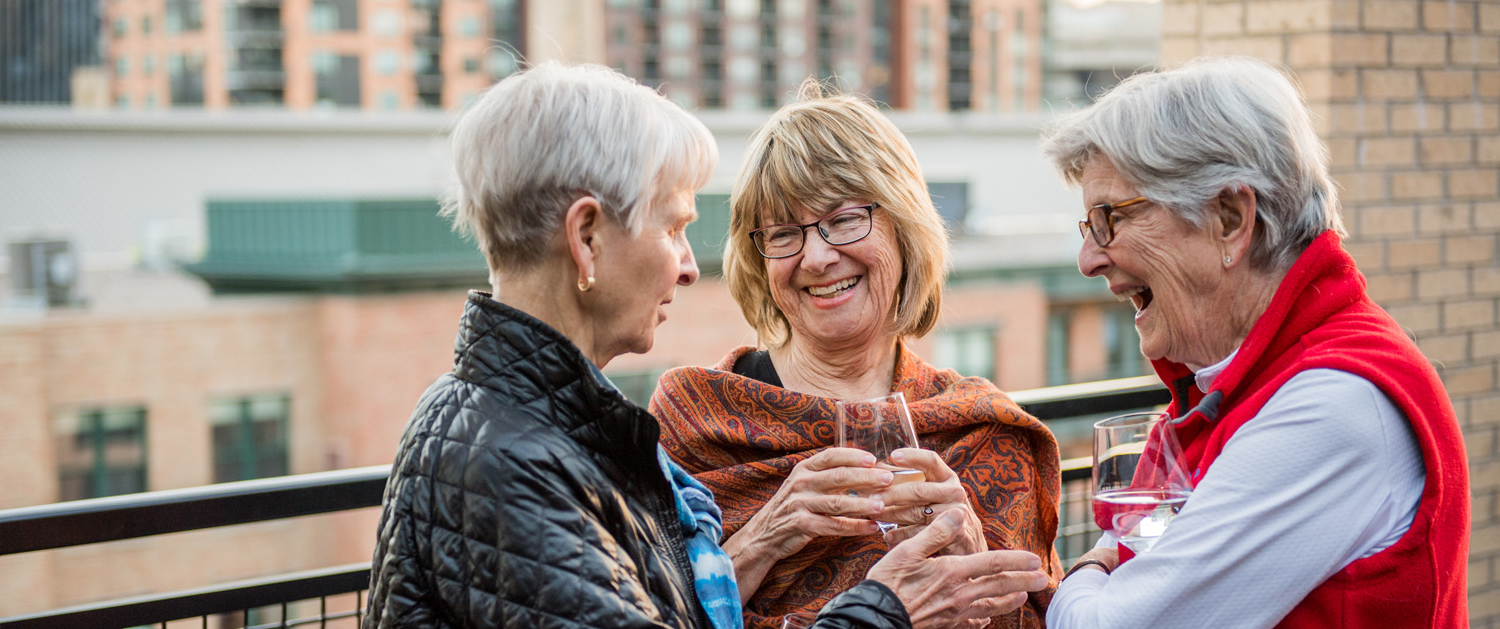 Three women enjoying drinks on a balcony