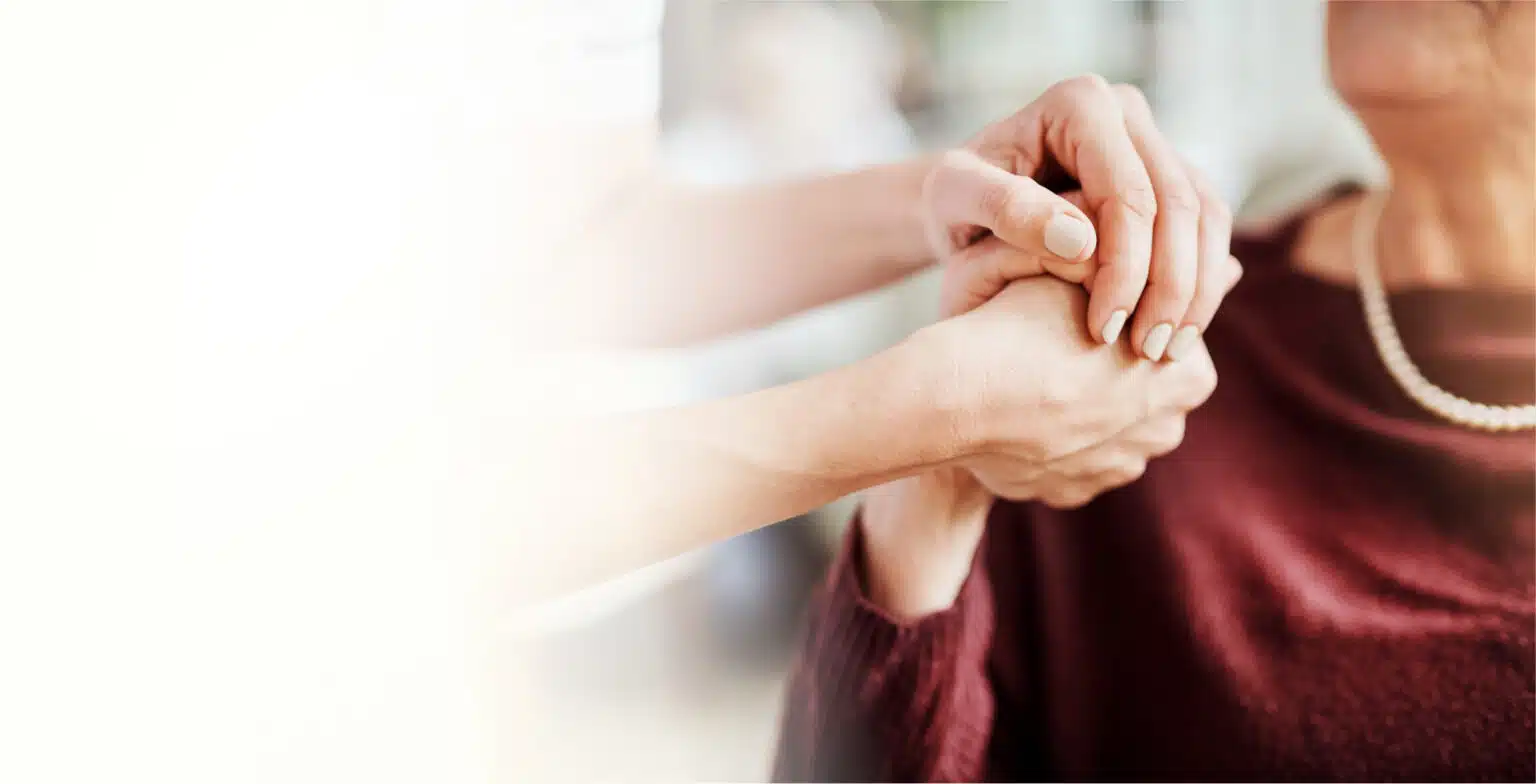 Staff member holding a resident's hand warmly.