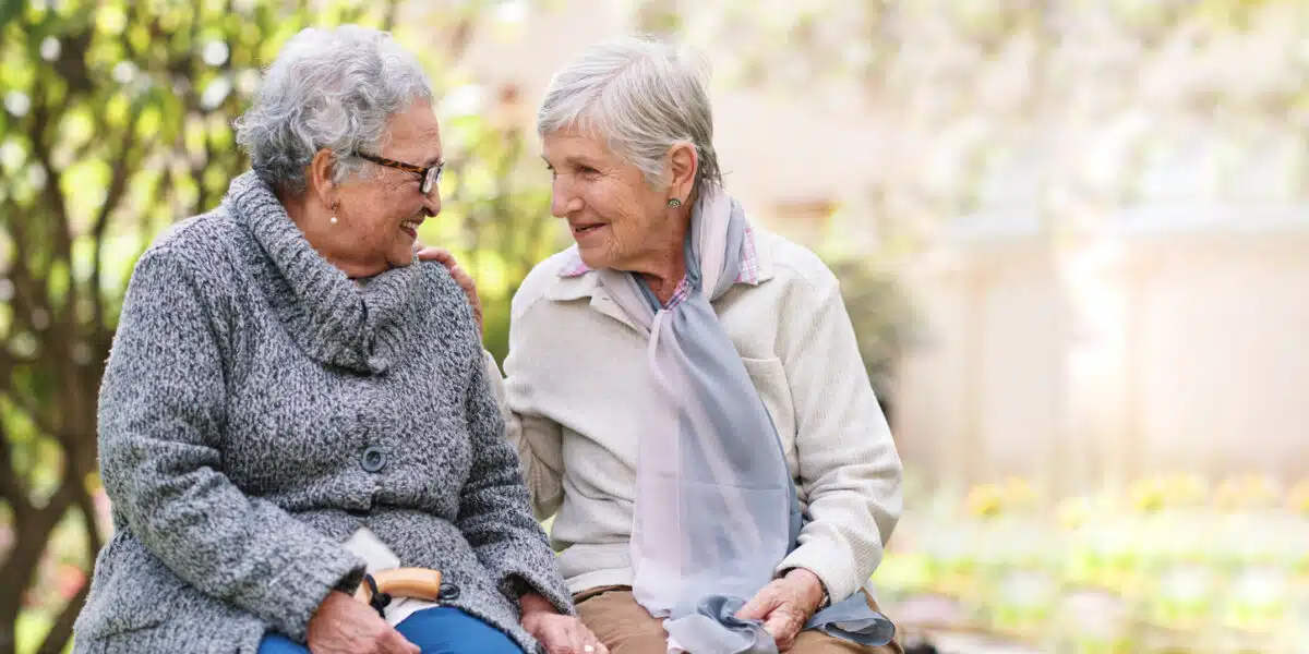 Two elderly women enjoying a conversation outdoors.