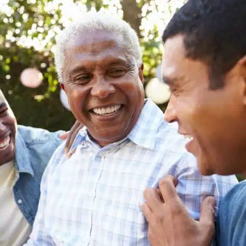 Smiling senior man with two younger men outdoors