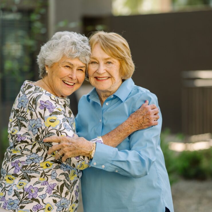 Two senior women embracing outdoors.