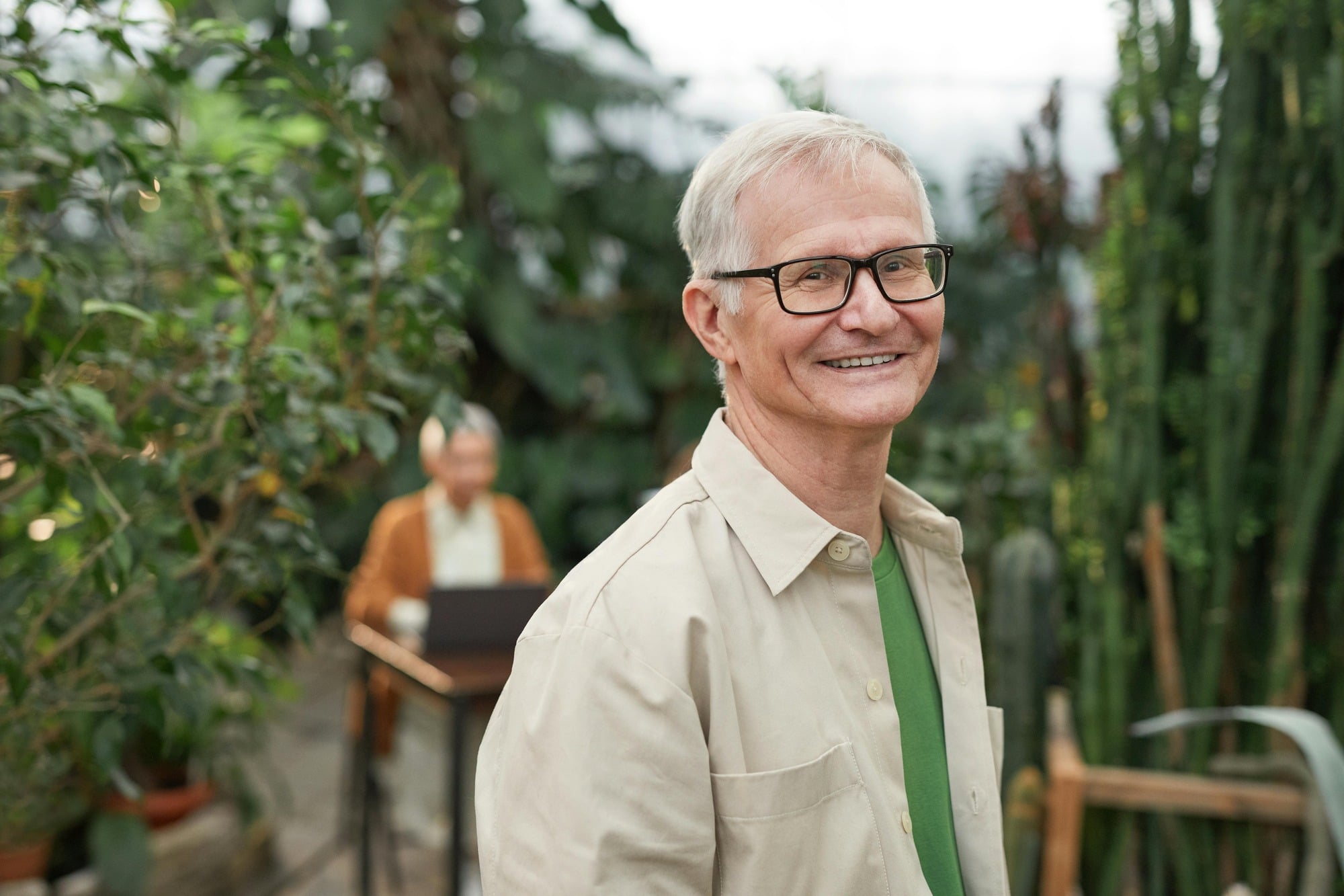 Senior man smiling in a greenhouse setting