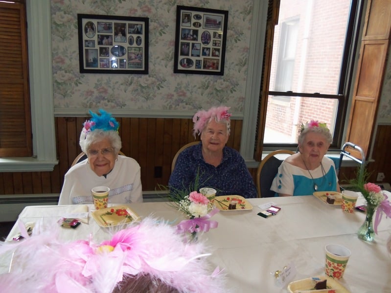 Three elderly women celebrating with floral headpieces