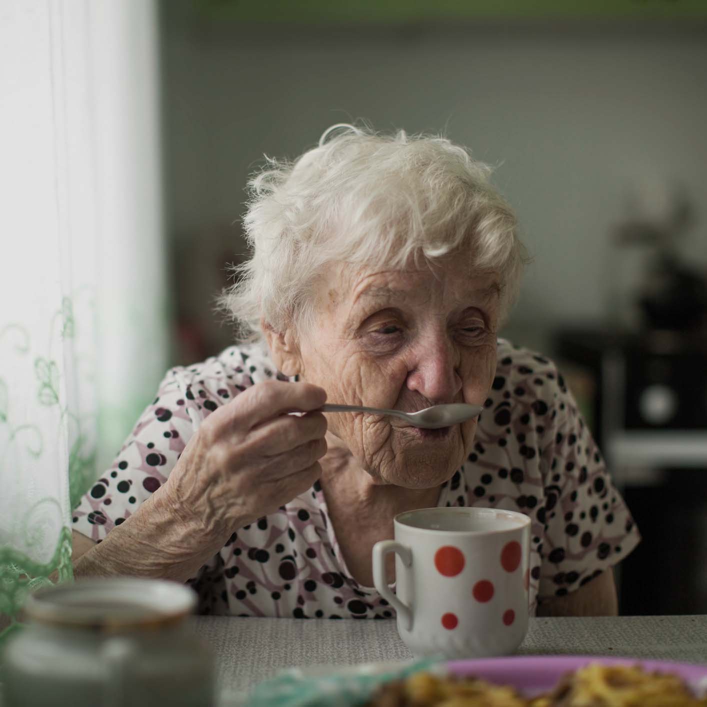 Elderly woman enjoying a cup of tea.