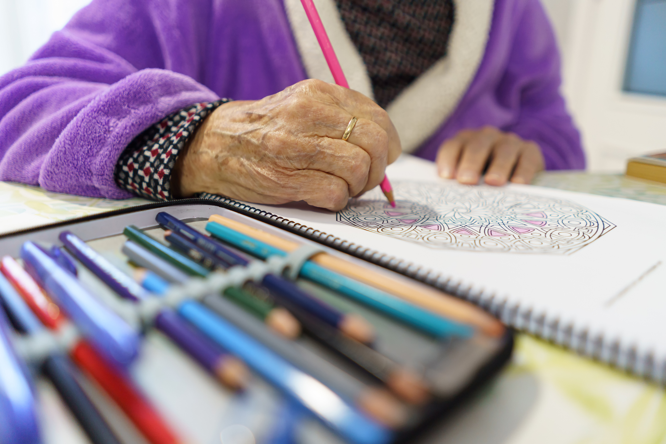Elderly person coloring in a book.
