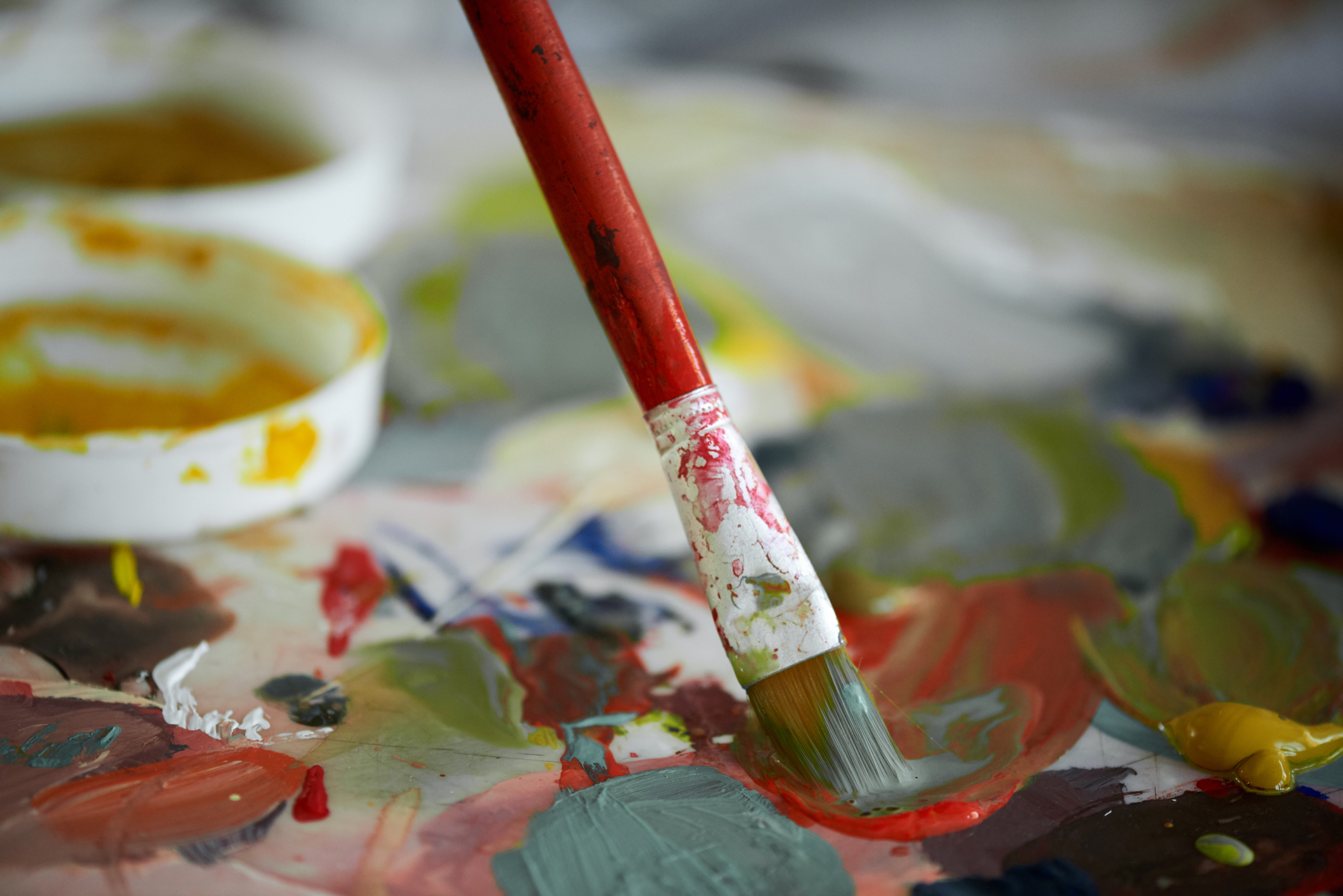 Paintbrush on a palette with colorful paint.